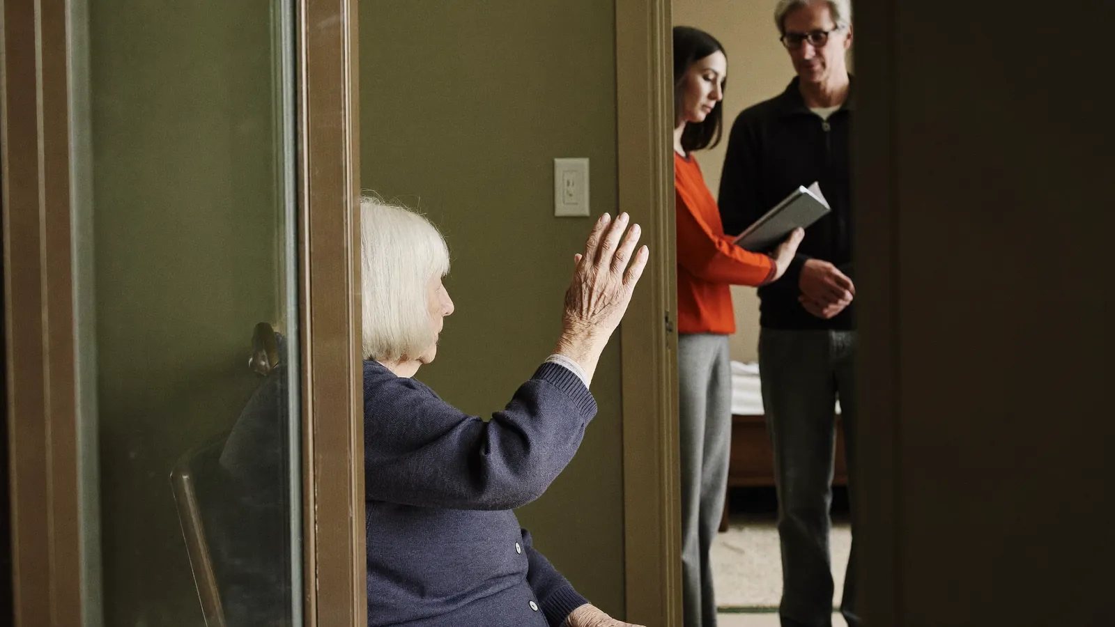An older woman staying in another room while her daughter speaks with an advisor