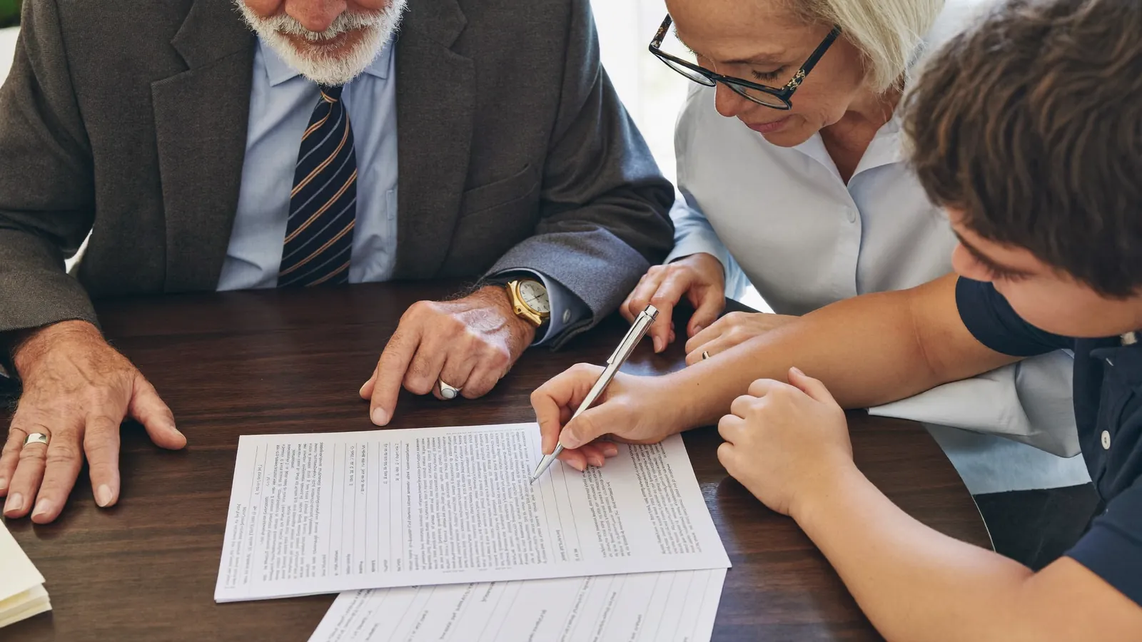 A family reviewing an assisted living contract page by page at a kitchen table