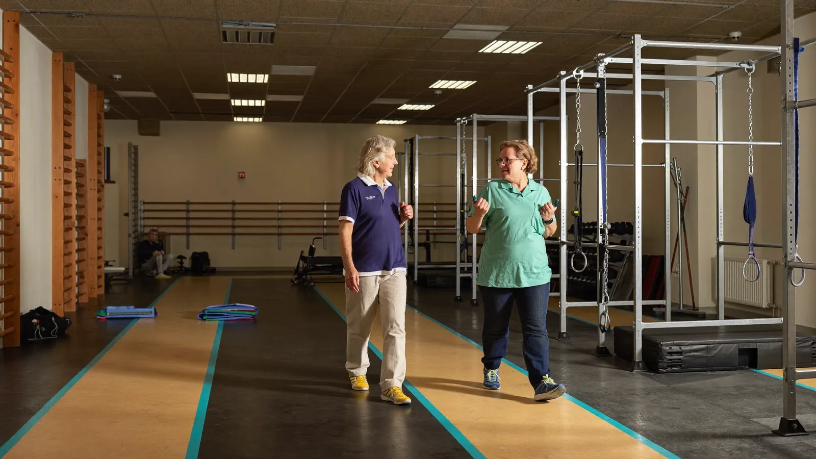An older man walking with a physical therapist in a rehabilitation gym