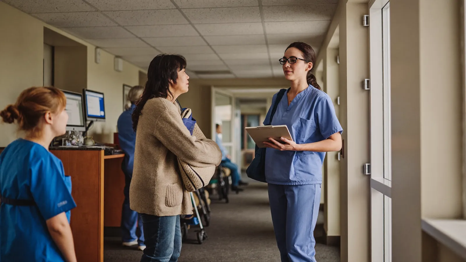 A family member asking an assisted living caregiver questions in a hallway