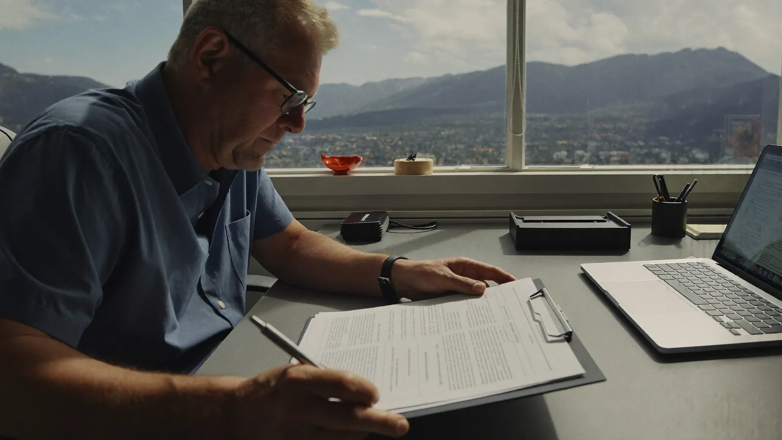 A man reviewing printed Colorado care community inspection reports at a desk