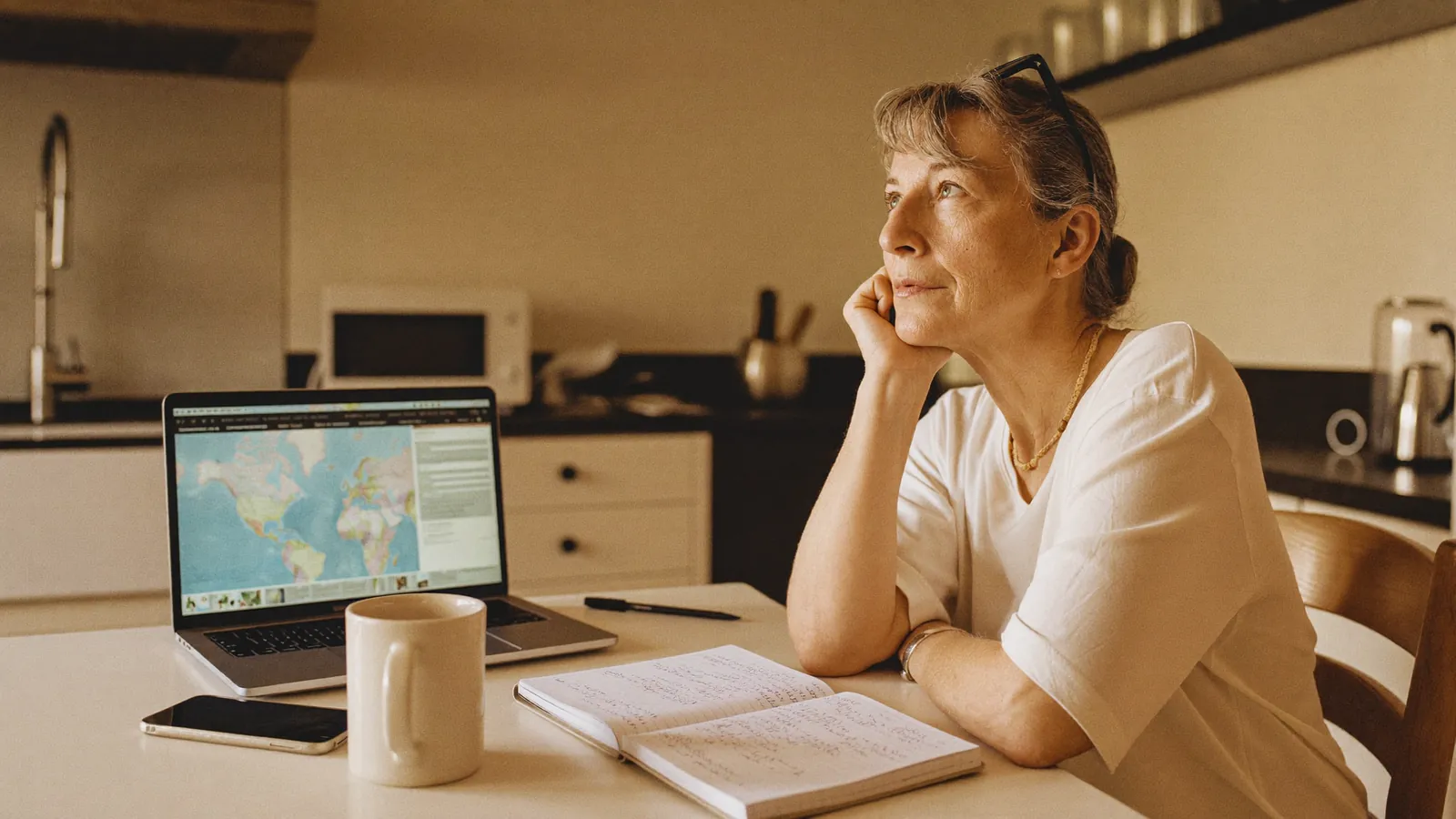 A woman researching senior living communities on a laptop with handwritten notes beside her